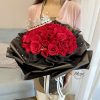 鮮やかな赤いバラの花束に王冠と黒いラッピング、白いかすみ草と光るライトがアクセント。