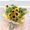 wrapped in light brown and peach, this bouquet features sunflowers, red berries and eucalyptus leaves.