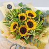 sunflower bouquet with red berry and eucalyptus in light brown and peach wrapping.