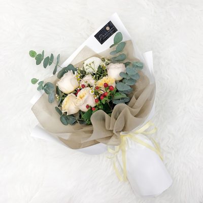 bouquet of champagne colour garden roses, red berries, white chrysanthemum ping pong, eucalyptus and fillers in a white wrapper.