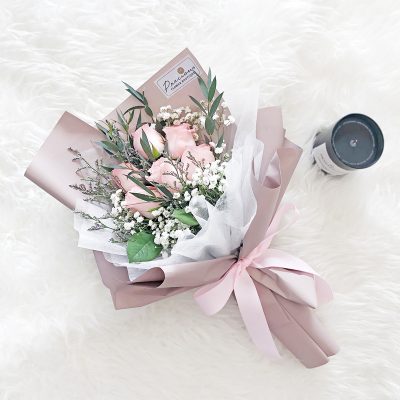 sweet bouquet of 6 stalks of pink roses, baby's breath and green leaves in a pink wrapper.