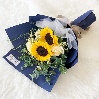 bouquet of 2 stalks sunflowers, champagne colour roses, eucalyptus and fillers in a blue wrapper.