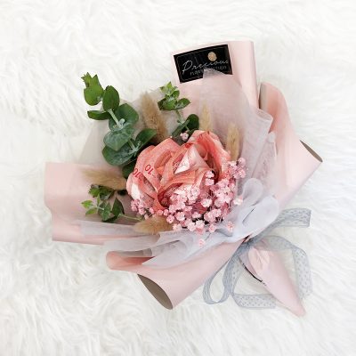 creative money bouquet with rose-shaped cash, pink baby’s breath and eucalyptus in a pink wrapper.