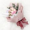 bouquet of pink roses, carnation sprays, baby’s breath and eucalyptus in dusty pink and white wrapper with wine red ribbon.