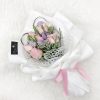 bouquet of pink roses and lilac eustoma with fillers wrapped in white wrapper and pink ribbon.