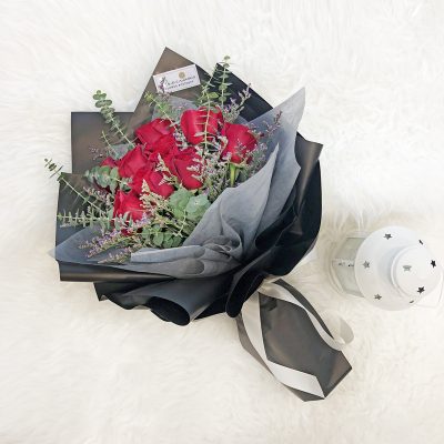 bouquet of red roses with eucalyptus and misty blue wrapped in black and grey wrapper with ribbon.