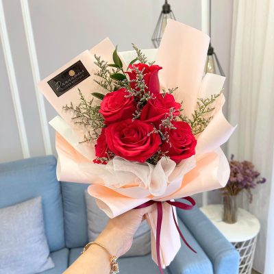 bouquet of red roses and caspia wrapped in peach colour wrapper with wine colour ribbon.