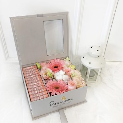 flower gift box with pink gerbera, pink roses, cotton flowers and banknotes in grey box.