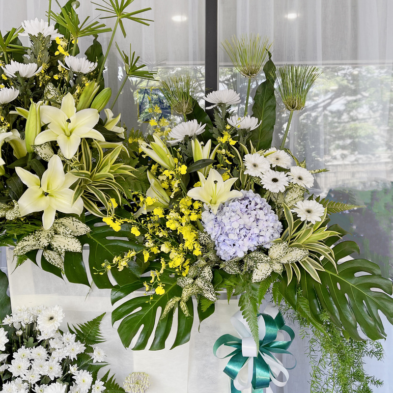 funeral flower with a blend of white gerberas, lilies, chrysanthemums and hanging greenery on a tall floral stand