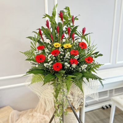 congratulations flower stand featuring red ginger, sunflower and red gerbera arranged in a tall wooden stand with green foliage and white filler flowers