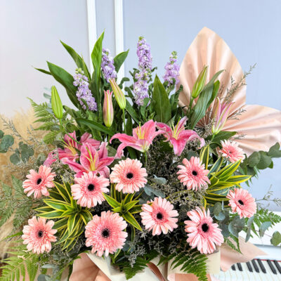 flower bouquet arrangement showcasing pink gerberas and stargazer lilies with matthiola flowers, surrounded by green foliage and decorative wrapping.