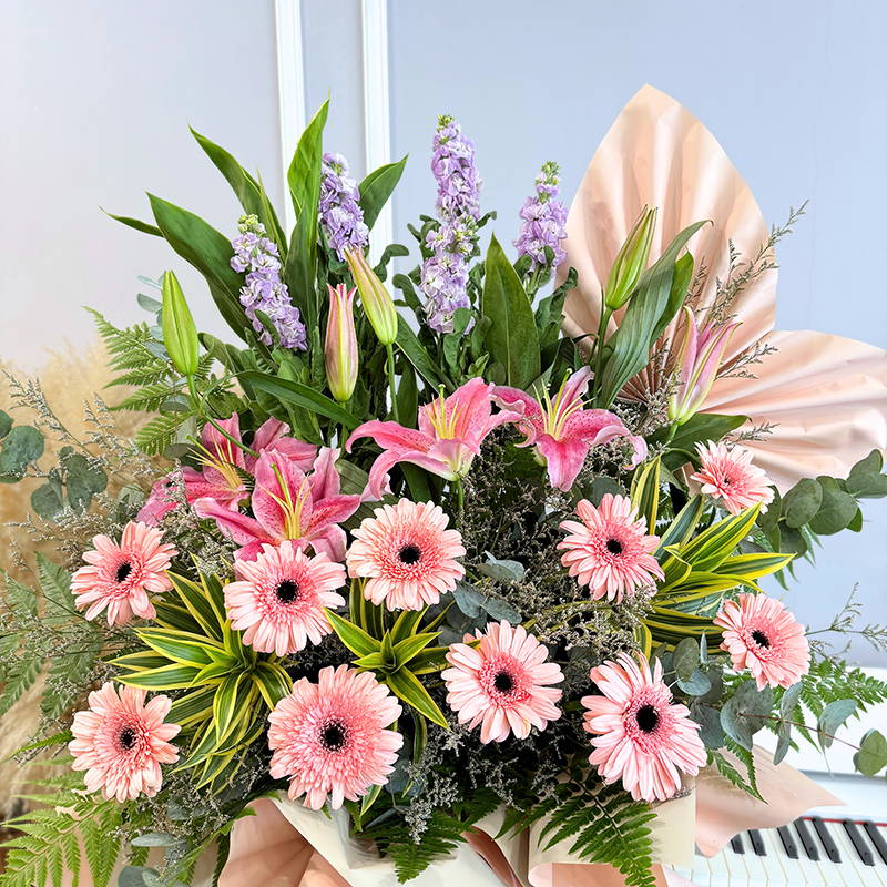 flower bouquet arrangement showcasing pink gerberas and stargazer lilies with matthiola flowers, surrounded by green foliage and decorative wrapping.