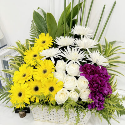 condolences flower basket arrangement with white chrysanthemum, yellow gerbera, white rose and purple carnation in a white basket