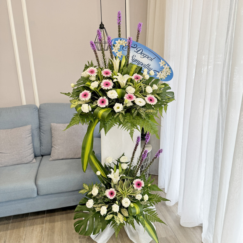 funeral flower stand featuring pink gerbera, white eustoma, casablanca lily and tall liatris with lush green foliage