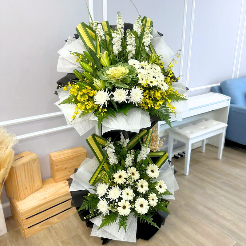 funeral flower stand with white matthiola, white casablanca lily and white gerbera in a layered stand arrangement