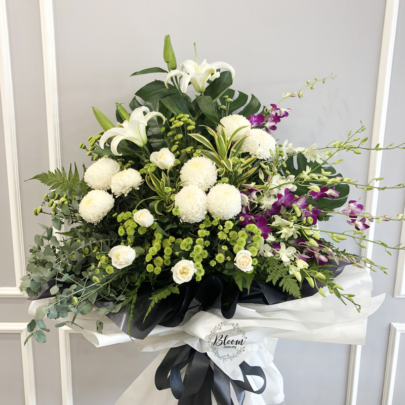 a funeral flower stand featuring white lilies, white chrysanthemums, white roses, pompom chrysanthemums, and clusters of purple orchids on a 175cm stand with layered white and black wraps.