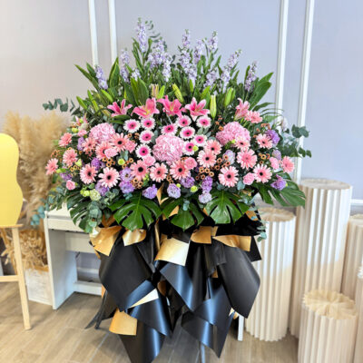 opening flower stand with pink stargazer lilies, pink gerberas and matthiola wrapped in black and gold paper