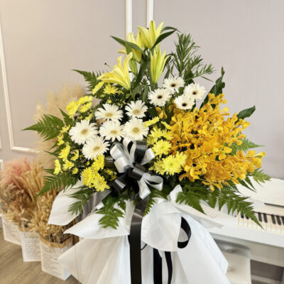 flower stand featuring yellow chrysanthemum pompom, white gerbera, orange orchid and conca d'or lily with decorative white wrap