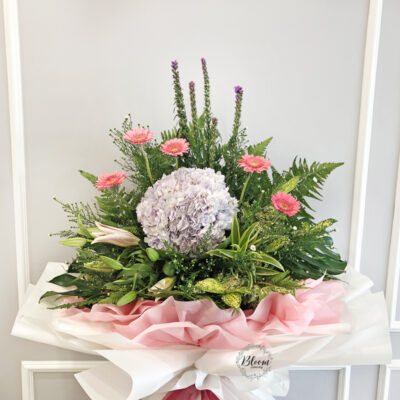 a tall opening flower stand with vibrant pink gerbera, lush hydrangea and elegant stargazer lily accented with liatris