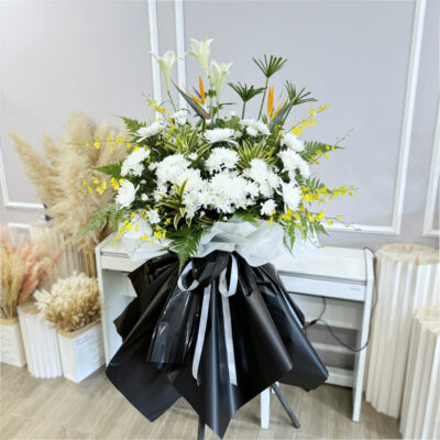 funeral stand with white madonna lily, bird of paradise, white chrysanthemum pompom and dancing lady in black and white wrapping