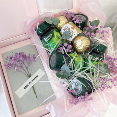 gift box featuring six bottles of brand's essence of chicken, three ferrero rocher chocolates, and purple coloured baby's breath flower bouquet wrapped in soft pink tissue.