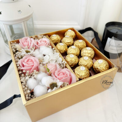 gift box with pink soap rose, cotton flower, baby's breath and ferrero rocher chocolates arranged neatly in a gold box