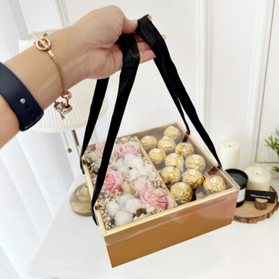 flower arrangement of pink soap rose and cotton flower paired with ferrero rocher chocolates in a divided gold gift box