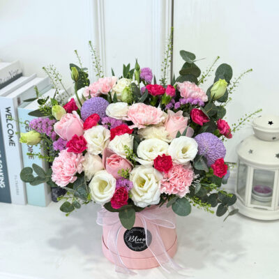 flower arrangement in a pastel pink box featuring pink carnation, pink rose, eustoma, and chrysanthemum pingpong flowers