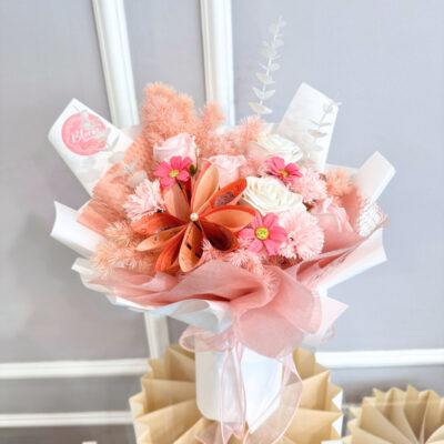 flower bouquet featuring pink and white soap roses with pink soap carnations and decorative cash flower accents wrapped in soft pink and white paper.