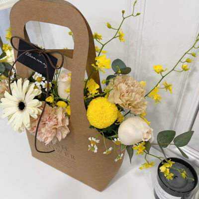 arrangement in a unique handbag box with imported carnations, dancing lady flowers, and chamomile