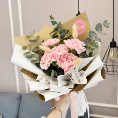 flower bouquet with five pink carnations and bunny tail wrapped in white and gold paper with green leaves
