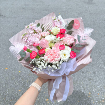 flower bouquet with pink rose, pink carnation, white eustoma, baby's breath, and feather accents wrapped in soft pink paper