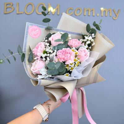 a flower bouquet featuring pink carnation and pink rose with baby's breath and chamomile wrapped in beige and white paper tied with a pink ribbon
