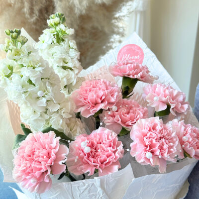bouquet of pink carnation and white matthiola flowers arranged with textured white wrapping