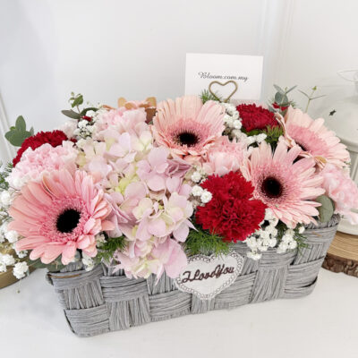 flower basket featuring pink gerbera, pink hydrangea, and red and pink carnations with greenery accents