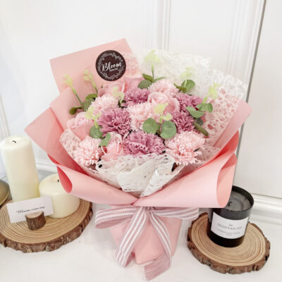 bouquet combining pink soap roses and carnations with green foliage and delicate white mesh wrapping