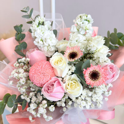 wrapped bouquet of mixed pink and white flowers including chrysanthemum pingpong and matthiola with delicate babyโs breath
