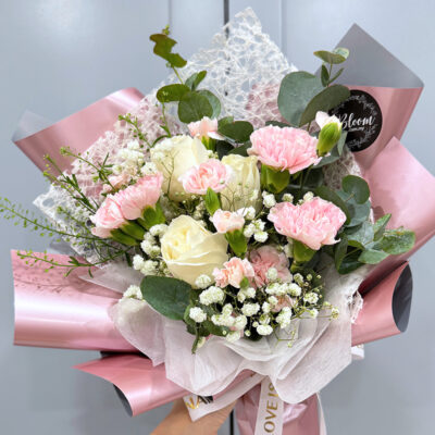 hand bouquet with white roses and pink carnations accented by baby's breath and wrapped in delicate pink and white layers